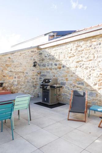 un patio avec des tables, des chaises et un grill dans l'établissement La Grange 1832 - A 10 mins d'Aubenas, à Saint-Étienne-de-Boulogne