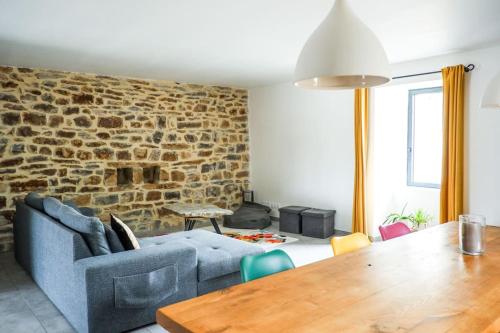 uma sala de estar com um sofá azul e uma parede de tijolos em La Grange 1832 - A 10 mins d'Aubenas em Saint-Étienne-de-Boulogne