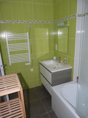 baño verde con lavabo, bañera y bañera en La petite maison, en Tauves