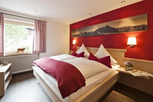 ein Schlafzimmer mit einem großen Bett mit einer roten Wand in der Unterkunft Im Höfle Ferienwohnungen in Mittelberg