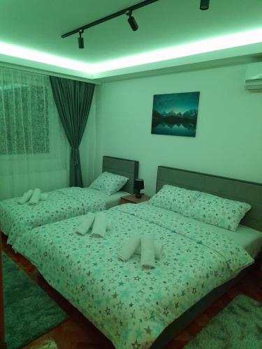 two twin beds in a bedroom with green sheets at Holiday apartaments 2 in Niš