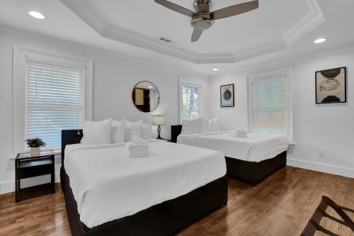 a white bedroom with two beds and a mirror at Buckheaddream Atlanta6bdrms Wbath In Every Room in Atlanta