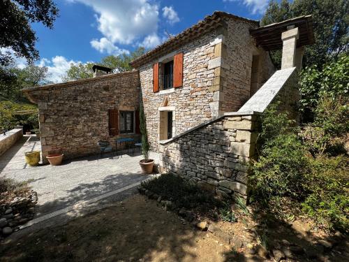 a small stone house with a patio in front of it at Le clos des songes. in Saint-Christol-de-Rodières