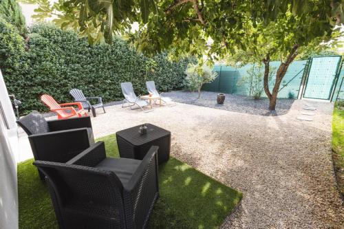 a patio with chairs and tables and a tree at Eden House, Cocon sensuel et romantique avec jacuzzi in Carpentras