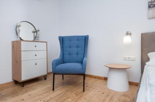 a bedroom with a blue chair and a table at Pokoje Sienkiewicza in Gliwice