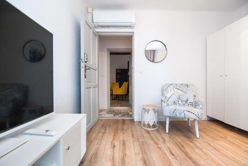 a white living room with a chair and a mirror at Pokoje Sienkiewicza in Gliwice