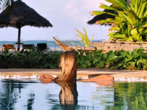 a woman sitting in the water in a pool at Pongwe Bay Resort in Pongwe