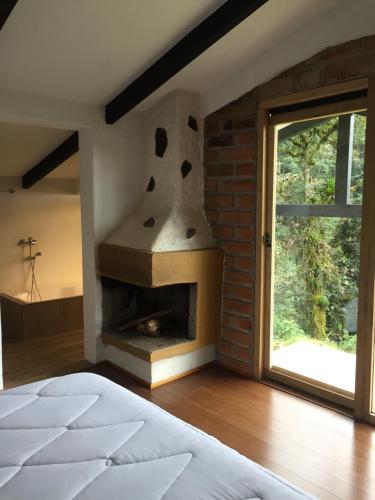 um quarto com uma lareira de tijolos ao lado de uma janela em Neblina Bird em Otavalo