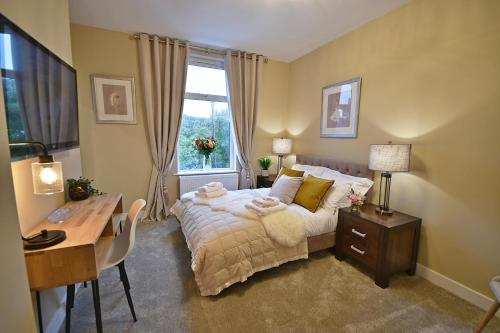 a bedroom with a bed and a desk and a window at Moat House in Rawtenstall