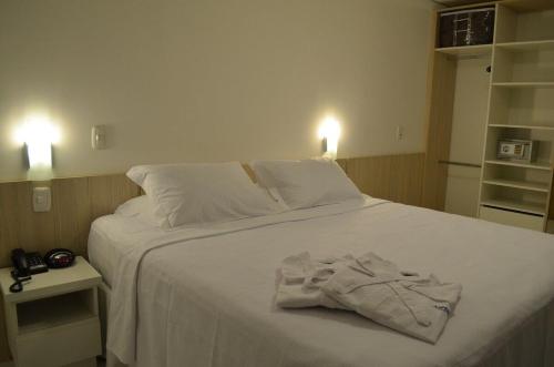 ein Schlafzimmer mit einem weißen Bett und Handtüchern darauf in der Unterkunft Executive 206 Sem Garagem in Caxias do Sul