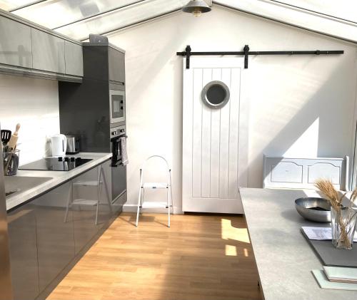 a kitchen with a white door and a wooden floor at Lovely spacious flat with sea views, sunsets, garden and woodburner in Sennen