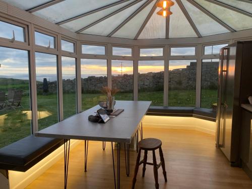 a conservatory with a table and chairs and a large window at Lovely spacious flat with sea views, sunsets, garden and woodburner in Sennen