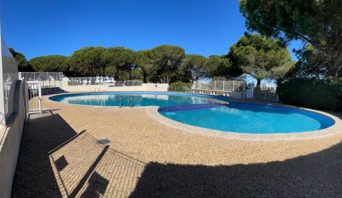 - une grande piscine d'eau bleue dans la cour dans l'établissement Superbe studio, terrasse, piscine, parking, au Grau-du-Roi