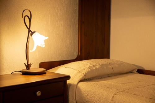 a lamp on a wooden table next to a bed at La Maison de Elisa - A pochi passi dallo SCI in Courmayeur