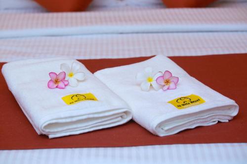 two towels with flowers on them sitting on a table at Ali Weta Safari Resort in Udawalawe
