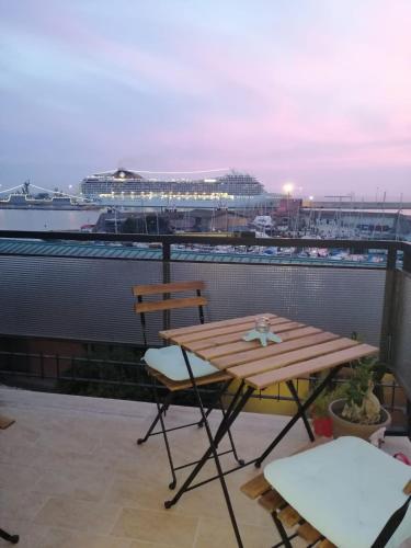 a table and chairs on a balcony with a cruise ship at Be Your Home - Guest House Colors in Civitavecchia