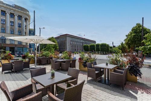 a patio with tables and chairs and an umbrella at Radisson Blu Latvija Conference & Spa Hotel, Riga in Rīga