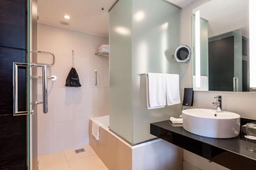 a white bathroom with a sink and a shower at Radisson Blu Elizabete Hotel, Riga in Rīga