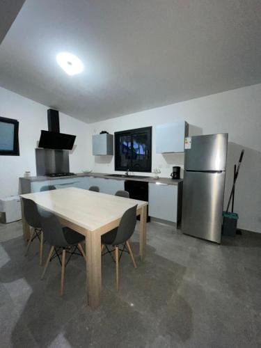 a kitchen with a table and a stainless steel refrigerator at L’étoilée in La Rivière