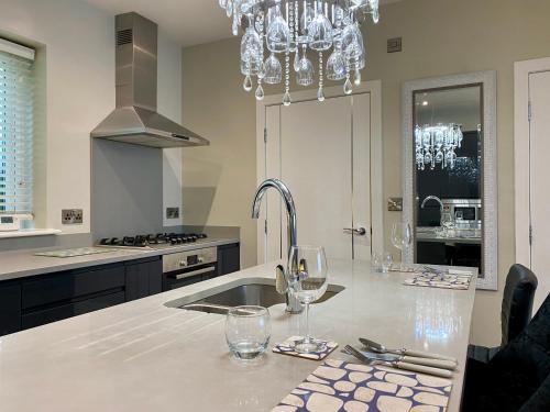 a kitchen with a chandelier and wine glasses on a counter at Executive Boutique Holiday Home - CS in Southport