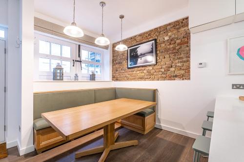 uma sala de jantar com uma mesa de madeira e uma parede de tijolos em London Choice Apartments - South Kensington - Mews House em Londres