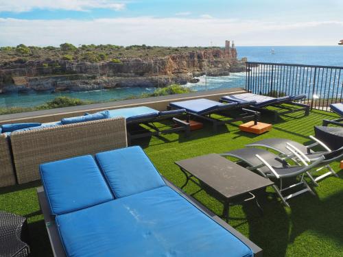 een patio met stoelen en tafels en uitzicht op de oceaan bij Hotel Rocamar in Cala Figuera