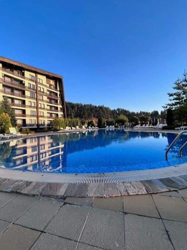 a large pool of blue water in front of a building at Cosy studios with mountain view near Bansko in Razlog