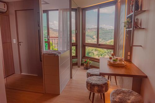 a room with a table and chairs and a large window at Blue Flat Pedra Azul - Com Vista pra Pedra in Pedra Azul