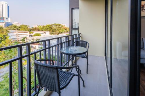 a balcony with two chairs and a table at Amp Am House Bangkok Hotel in Bangkok