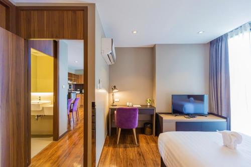 a hotel room with a bed and a desk and a tv at Amp Am House Bangkok Hotel in Bangkok