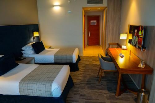 a hotel room with two beds and a desk at Hotel Parada Linares in Linares