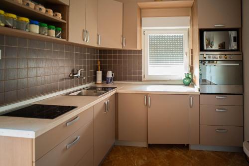 a kitchen with white cabinets and a sink and a window at Sun Garden in Čitluk