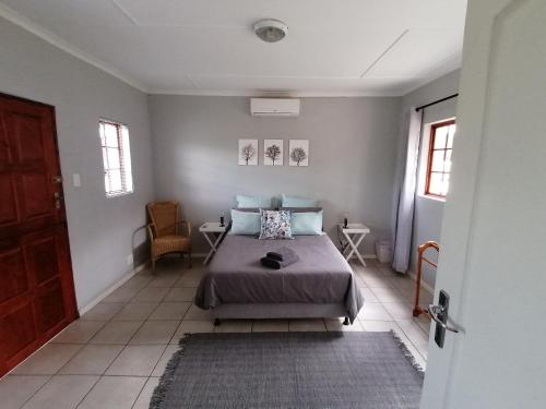 1 dormitorio con 1 cama y 1 silla en Aqua Farm Guesthouse, en Fort Beaufort