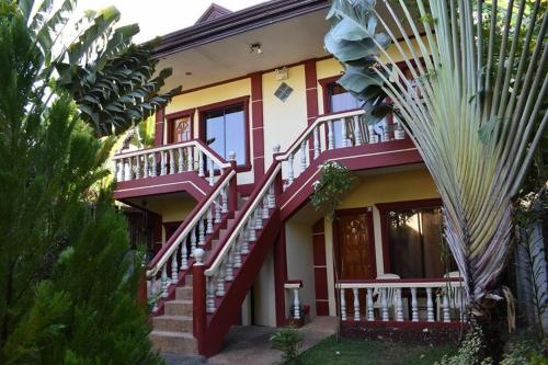 a red and yellow house with stairs and a palm tree at One 4 Da Road in Panglao