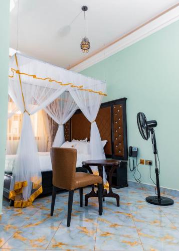 a bedroom with a bed and a desk and a chair at Romeos Hotel in Kampala