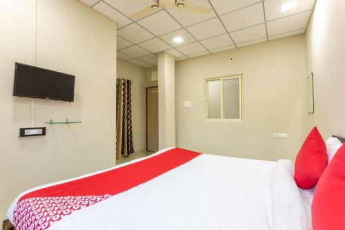 a bedroom with a bed with red pillows and a flat screen tv at JAGTARA RESIDENCY in Indore