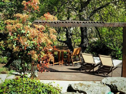 eine Holzterrasse mit Stühlen und einem Tisch im Garten in der Unterkunft Fragas do Lobo - Casa da Azenha in Castelo Novo