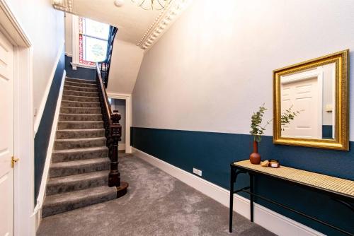 a stairway with blue walls and a gold framed mirror at St Johns, Wakefield - Self check in & free parking in Wakefield