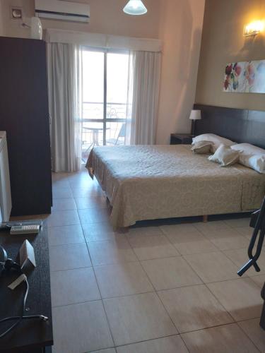 a bedroom with a bed and a large window at ALBERTI APARTAMENTS in Campana