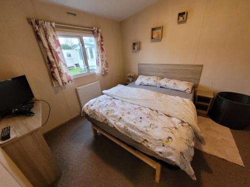 a bedroom with a bed and a television and a window at K & K Caravan Southview in Skegness