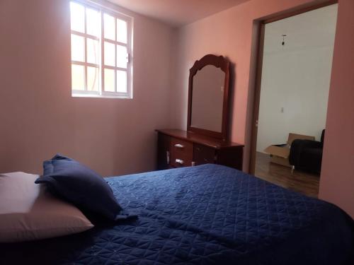 um quarto com uma cama azul e um espelho em Posada MemeLulu em Nanacamilpa
