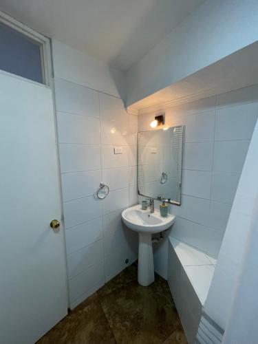 een witte badkamer met een wastafel en een spiegel bij Centromar 302 a pasos de todo in Viña del Mar