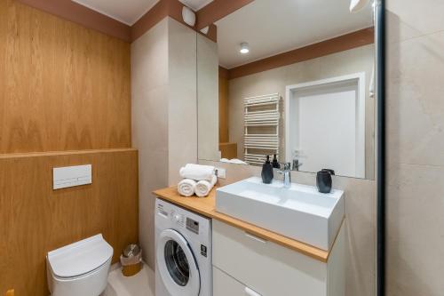 a bathroom with a sink and a washing machine at Apartament WILLOW TREE SurfingBird Dźwirzyno in Dźwirzyno