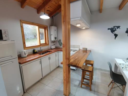 una pequeña cocina con mesa de madera y refrigerador. en Los Robles Patagonia en Esquel