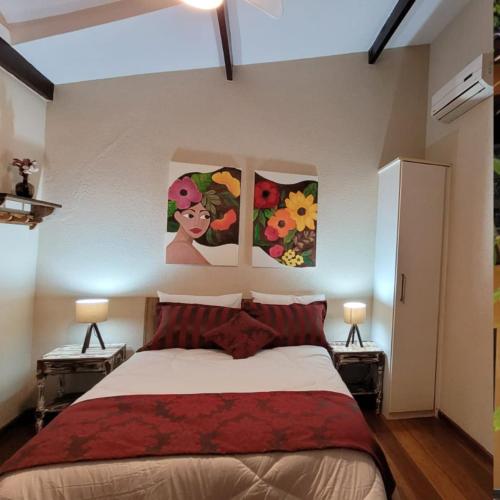 um quarto com uma cama com duas pinturas na parede em Chalé Penedo RJ - Centro em Penedo