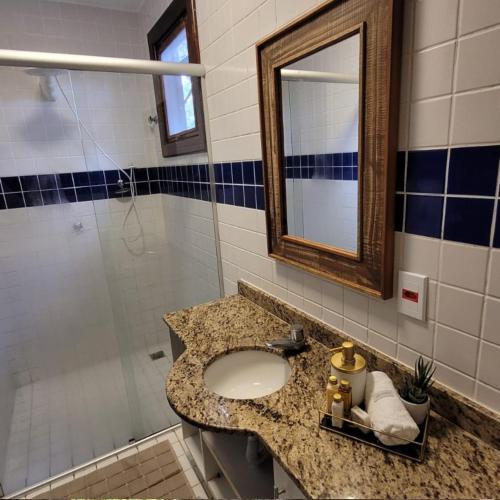 een badkamer met een wastafel, een spiegel en een douche bij Chalé Penedo RJ - Centro in Penedo