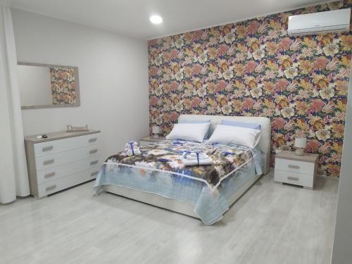 een slaapkamer met een bed met bloemenbehang bij Shine Flowers Room in Scordia