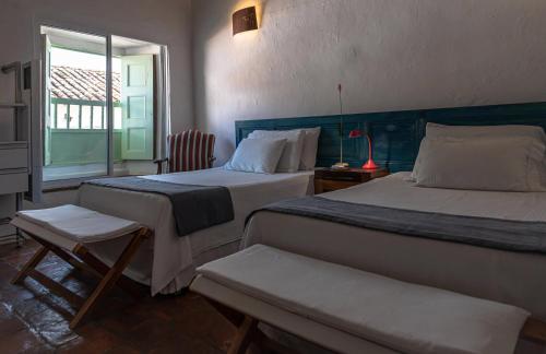 a bedroom with two beds and a chair and a window at La Nube Posada in Barichara