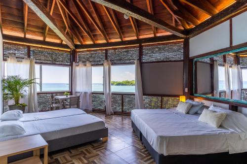 two beds in a room with large windows at Rosario EcoHotel in Isla Grande