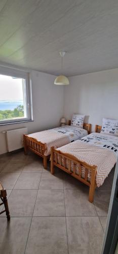 deux lits dans une chambre avec une grande fenêtre dans l'établissement La Colonie, à Publier